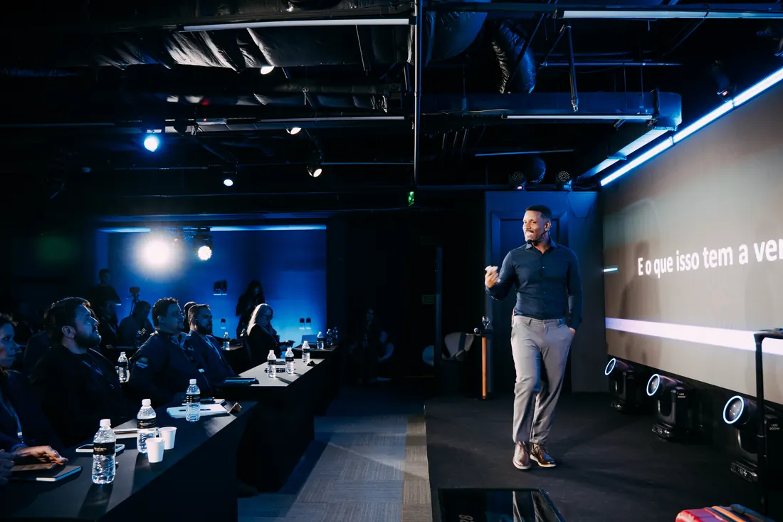 Tiago Rocha falando ao público em palco corporativo